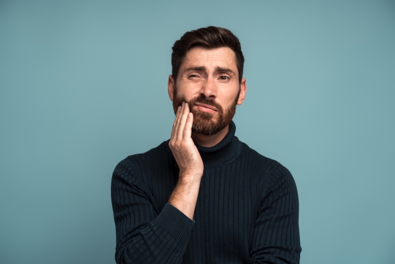 A man holding his hand up to his mouth because of symptoms of periodontal disease