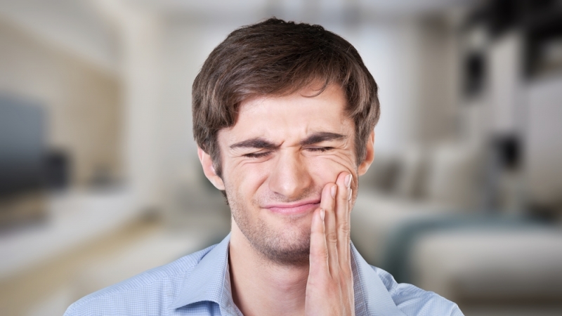 A man with TMJ pain holding his jaw